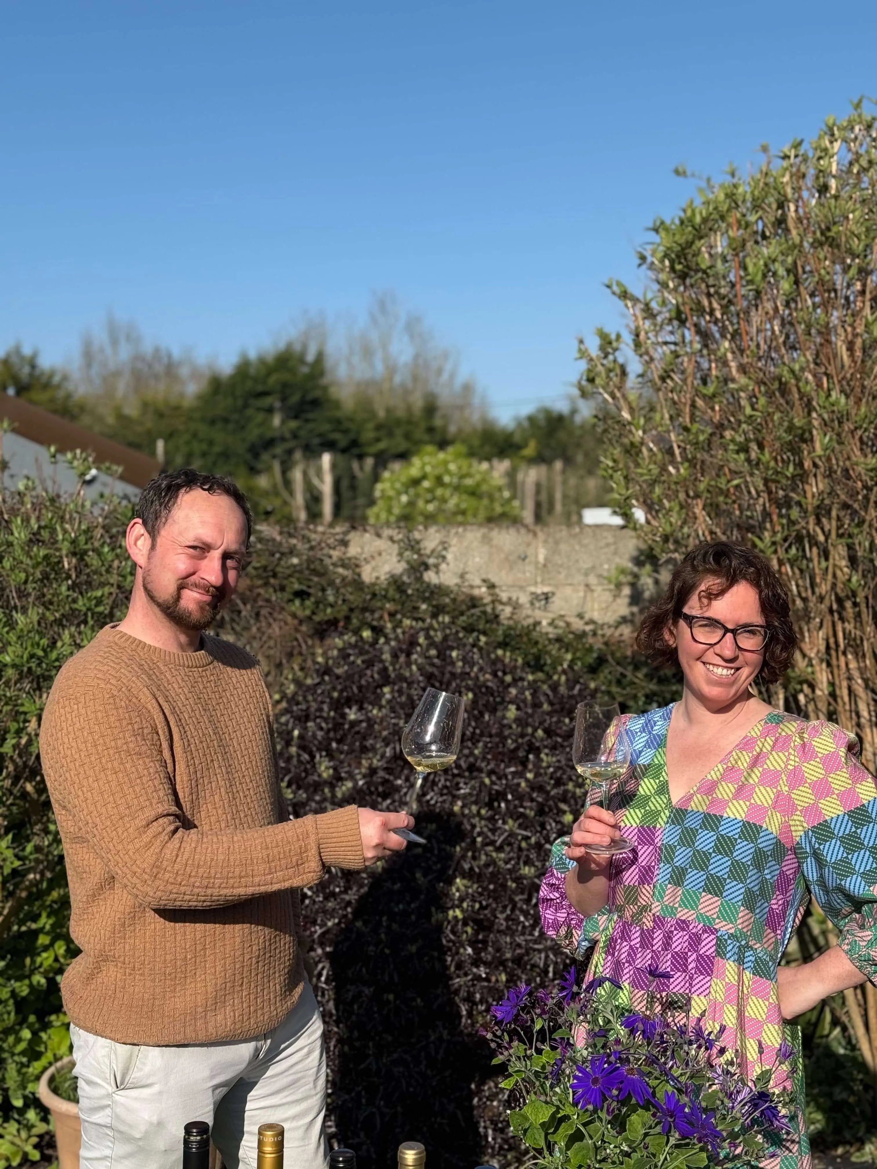 Michelle and Tony, founders of The Nude Wine Co, two people holding glasses of wine in a garden setting